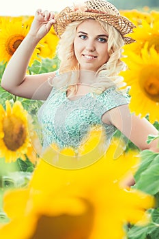 Portrait of a beautiful smiling blonde girl in a straw hat outdoors