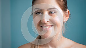 Portrait of beautiful smiling brunette woman looking at herself in mirror at bathroom