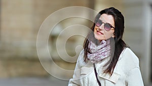 Portrait of beautiful smiling brunette woman in sunglasses posing looking at camera at outdoor