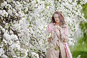 Portrait of a beautiful smiling brunette young women  in blossom apple tree garden in spring time. Enjoy Nature. Healthy girl