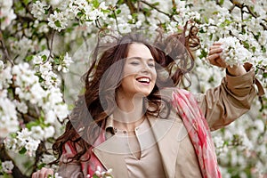 Portrait of a beautiful smiling brunette young women  in blossom apple tree garden in spring time. Enjoy Nature. Healthy girl