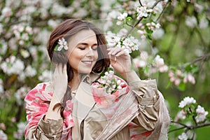 Portrait of a beautiful smiling brunette young women  in blossom apple tree garden in spring time. Enjoy Nature. Healthy girl