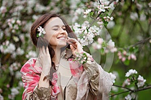 Portrait of a beautiful smiling brunette young women  in blossom apple tree garden in spring time. Enjoy Nature. Healthy girl