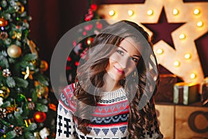 Portrait of beautiful smiling curly women near christmas tree. Celebration