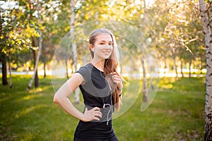 Portrait of a beautiful smiling girl in a sports uniform with flowing hair listening to music in headphones