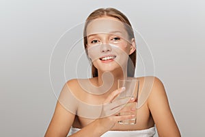 Portrait of beautiful smiling lady without makeup with transparent patches under eyes holding glass with pure water