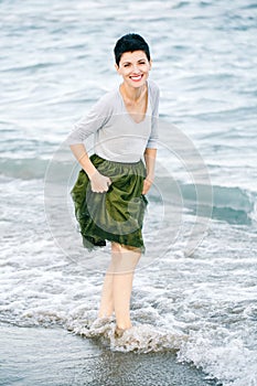 Portrait of beautiful smiling laughing Caucasian brunette woman with short hair in grey shirt, green olive tutu tulle skirt
