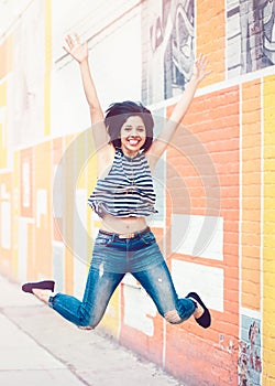 Portrait of beautiful smiling laughing young hipster latin hispanic girl woman jumping up in air