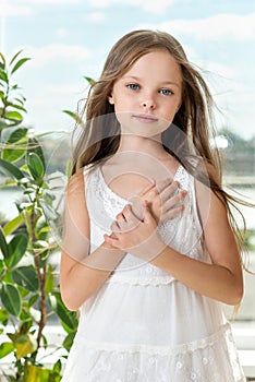 Portrait of beautiful smiling little girl with long healthy hair front of the window