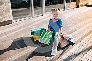 Portrait of beautiful smiling little girl wearing with shopping bag outdoors