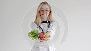 Portrait of a beautiful smiling red-haired female doctor offering you vegetables healthy eating concept.