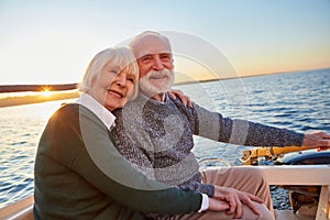 Portrait of beautiful smiling senior couple holding hands, hugging and relaxing together while sitting on the side of