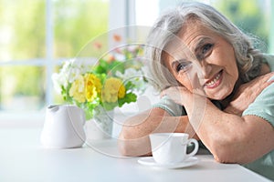 Portrait of beautiful smiling senior woman with cup of tea at kitchen