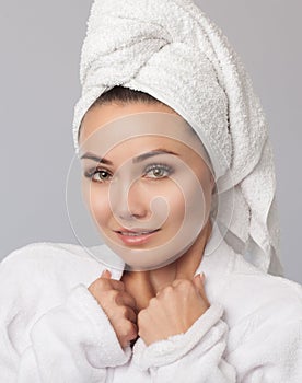 Portrait of a beautiful, smiling woman with clean skin in a white bathrobe after taking a shower. Women`s cosmetology and daily