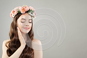 Portrait of beautiful smiling woman with clear skin, long shiny hair and flowers. Skincare and facial treatment concept