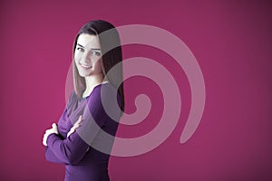 Portrait of beautiful smiling woman with crossed arms on pink ba