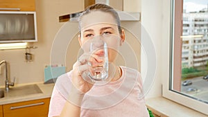 Portrait of beautiful smiling woman drinking water on kitchen before breakfast. Healthy nutrition and lifestyle