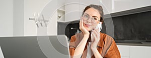 Portrait of beautiful smiling woman working from home, talking on mobile phone, calling client, self-employed