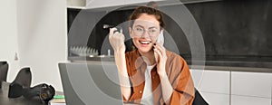 Portrait of beautiful smiling woman working from home, talking on mobile phone, calling client, self-employed