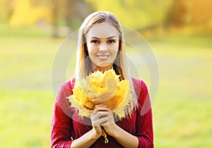 Portrait of beautiful smiling woman with yellow maple leafs autumn