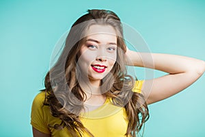 Portrait of a beautiful smiling woman in yellow t-shirt and red lips on a blue background. Closeup, horizontal, copys pace