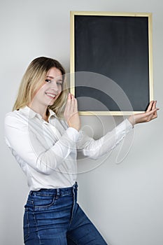 Portrait of a beautiful smiling young blonde woman holding a blank whiteboard at face height with room to add text