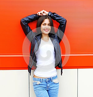 Portrait beautiful smiling young brunette woman wearing a rock black leather jacket and jeans posing in city