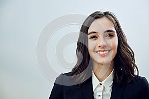 portrait of a beautiful smiling young businesswoman wearing black jacket on a white background looking at camera