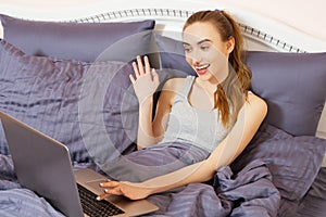 Portrait beautiful smiling young white woman laying in bed relaxing using working on her laptop computer. Positive human face