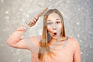 Portrait of a beautiful smiling young woman comb hair, on a background of gray sparkles