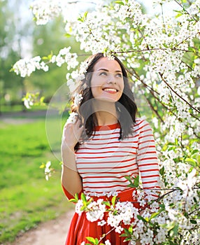 Portrait beautiful smiling young woman enjoying flowering garden