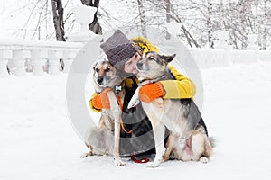 Portrait of beautiful smiling young woman with her two dogs in a snowy winter park