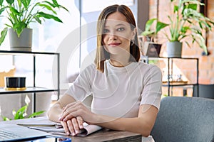 Portrait of beautiful smiling young woman sitting at table in coworking cafe