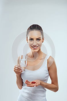 Portrait Of Beautiful Smiling Young Woman With Vitamin Pills. Happy Girl Holding Medications And Glass Of Fresh Water