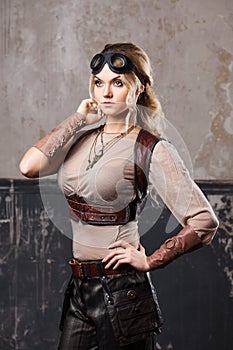 Portrait of a beautiful steampunk woman in Aviator glasses over grey background.