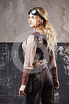 Portrait of a beautiful steampunk woman in Aviator glasses over grey background.