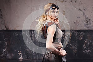 Portrait of a beautiful steampunk woman in Aviator glasses over grey background.