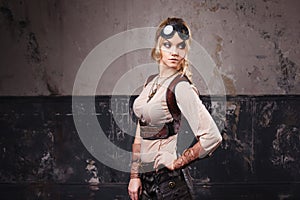 Portrait of a beautiful steampunk woman in Aviator glasses over grey background.