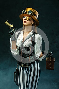 Portrait of a beautiful steampunk woman holding a gun
