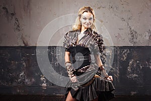 Portrait of a beautiful steampunk woman in the lush striped blouse, over grunge background.
