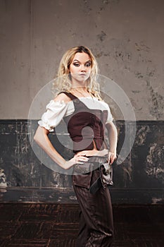 Portrait of a beautiful steampunk woman in a pant suit with vest, over grunge background.