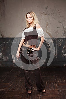 Portrait of a beautiful steampunk woman in a pant suit with vest, over grunge background.