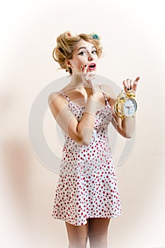 Portrait of a beautiful surprised young woman looking at camera & showing alarm clock expressing amazement & looking at camera