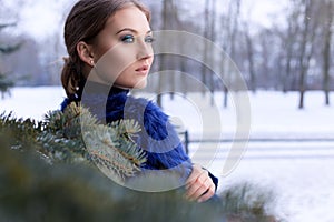 Portrait of a beautiful sweet girl with a beautiful make-up near the Christmas tree in winter bright day