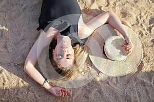 Portrait of a beautiful tanned sexy girl on the beach. Woman relaxing in swimsuit on the sand. Summer Vacation Concept