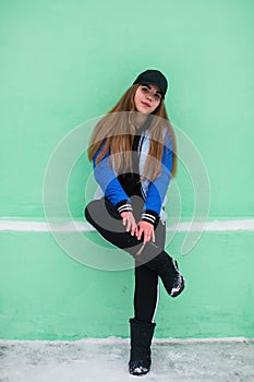 Portrait of beautiful teen girl near green wall in winter