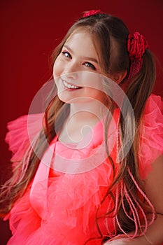 portrait of a beautiful teenage girl with ponytails in a pink elegant dress.