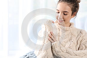 Portrait of beautiful teenage girl in warm cozy sweater on light background