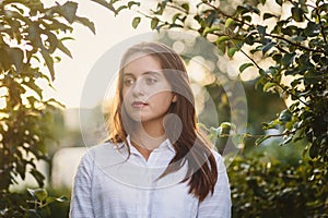 Portrait of beautiful teenage girl in white blouse in Apple orchard in summer