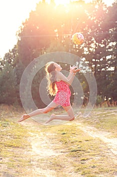 Portrait of Beautiful teenager girl  Is jumping and playing with ball at  summer sunset. Soft focused